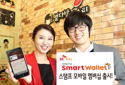 오른쪽 모델은 SK플래닛 ‘스마트월렛’, ‘스탬프’ 모바일 멤버십 출시라고 적힌 배너를 들고 있습니다. 왼쪽 모델은 앱 구동화면을 들고 있습니다.