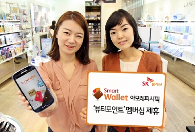 SK플래닛 스마트월렛 홍보 사진입니다. 오른쪽 모델은 스마트월렛, 아모레퍼시픽 뷰티포인트 멤버십과 제휴라고 적힌 배너를 들고 있습니다. 왼쪽 모델은 앱 구동화면을 들고 있습니다.