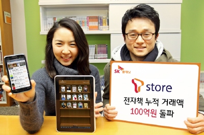 T스토어 홍보 사진입니다. 왼쪽 모델이 핸드폰 앱 구동화면을 보여주고 있으며 오른쪽 모델은  T스토어, 전자책 거래액 100억 원 돌파라고 적힌 배너를 들고 있습니다.