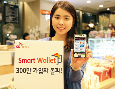 모델이 앱 구동화면을 들고 있으며 SK플래닛, ‘스마트월렛’ 가입자 300만 돌파! 라고 적힌 배너를 들고 있습니다. 