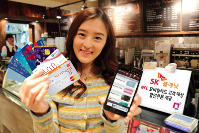 모델이 핸드폰 앱 구동화면을 들고 있으며 모델 뒤로 SK플래닛, ‘명동 NFC존’ 할인쿠폰 제공이라는 배너가 있습니다. 