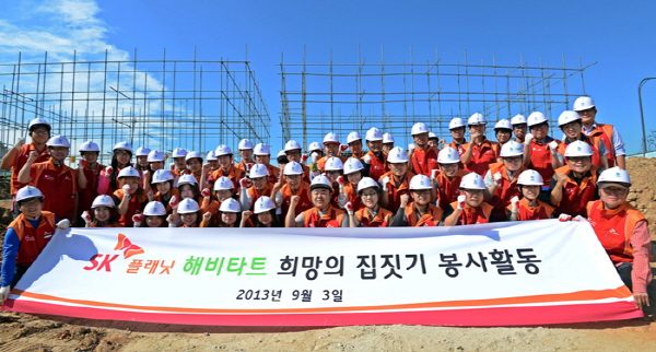 SK플래닛, T아카데미 앱 개발자들과 함께 희망의 집짓기 봉사활동을 진행한 후 촬영한 기념 사진입니다. 현수막에 SK플래닛 해피타트 희망의 집짓기 봉사활동이라는 문구가 적혀있습니다.