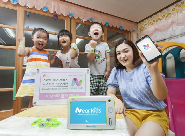 SK플래닛, 스마트 케어(Care) 서비스 ‘니어키즈(Near Kids) 출시 홍보 사진이 삽입되어 있습니다. 모델은 앱 구동화면을 들고 있으며 배너에는 스마트 케어 서비스 니어키즈 인증기관이라는 내용과 기계 사진이 놓여 있습니다.