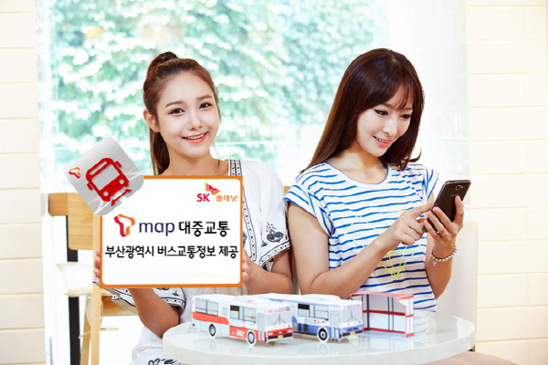 SK플래닛 T맵, 부산광역시 실시간 버스교통정보 제공 홍보 사진이 삽입되어 있습니다. 왼쪽 모델은 T맵 대중교통 부산광역시 버스 교통정보 제공이라고 적힌 배너를 들고 있습니다. 오른쪽 모델은 휴대폰을 들고 있습니다.