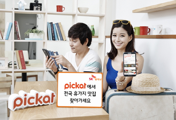 SK플래닛 피캣(pickat), 여름 휴가철 맞춤형 지역정보 제공 이벤트 홍보 사진입니다. 모델들은 앱 구동화면을 보여주고 있습니다. 모델 앞에는 피캣 BI와 피캣에서 전국 휴가지 맛집 찾아가세요라고 적힌 배너가 놓여있습니다.