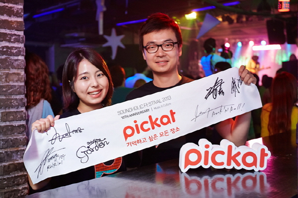 SK플래닛 피캣(Pickat)이 사운드홀릭 페스티발2013’ 프로모션을 진행한다는 홍보 사진입니다. 모델이 피캣 BI와 기억하고 싶은 모든 장소라는 문구가 적힌 배너를 들고 있습니다.