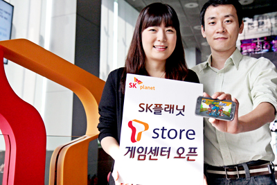 왼쪽 모델은 SK플래닛, T스토어 게임센터 오픈이라고 적힌 배너를 들고 있고 오른쪽 모델은 앱 구동화면을 보여주고 있습니다. 