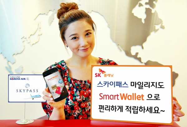 모델이 스카이패스 마일리지로 스마트 월렛으로 편리하게 적립하세요라고 적힌 배너를 들고 있으며 앱 구동화면을 들고 있습니다.