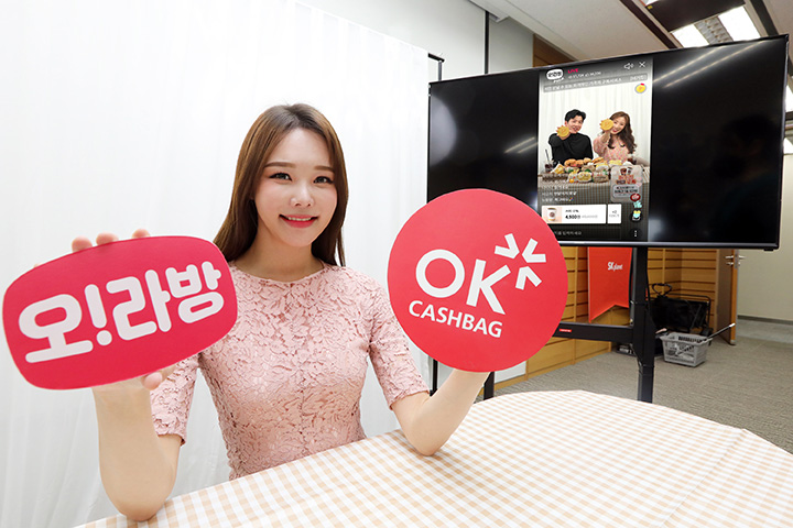 SK플래닛 OK캐쉬백,‘오!라방Pick’으로 라이브 커머스 본격화 SK플래닛이 OK캐쉬백,의 오!라방Pick으로 라이브 커머스 본격화 할 예정이다. 모델이 오!라방과 OK캐쉬백 BI 이미지를 들고 있으며, 뒤에 보이는 TV에는 라이브 방송이 나오고 있습니다.